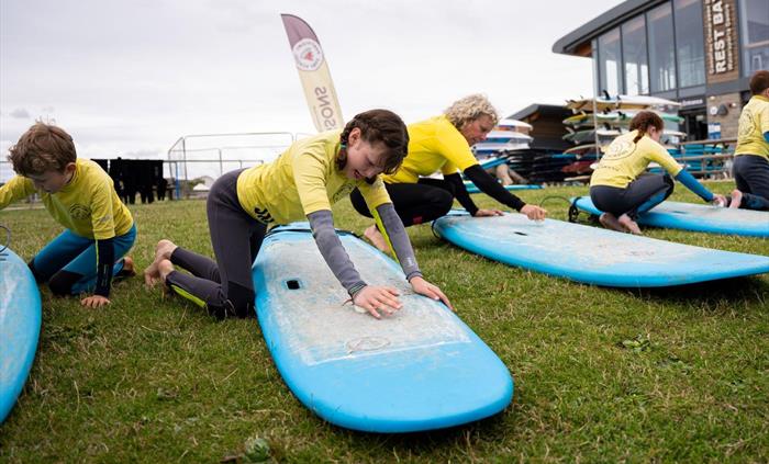Image of people practicing on surf boards on the grass.